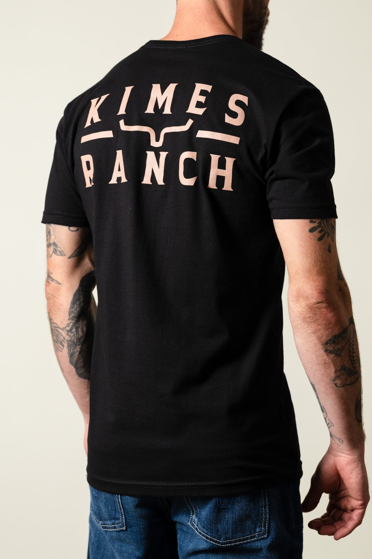 Back of Kimes Ranch Back Branded Shirt in black showing large logo print with stylized horn across upper back; #color_black