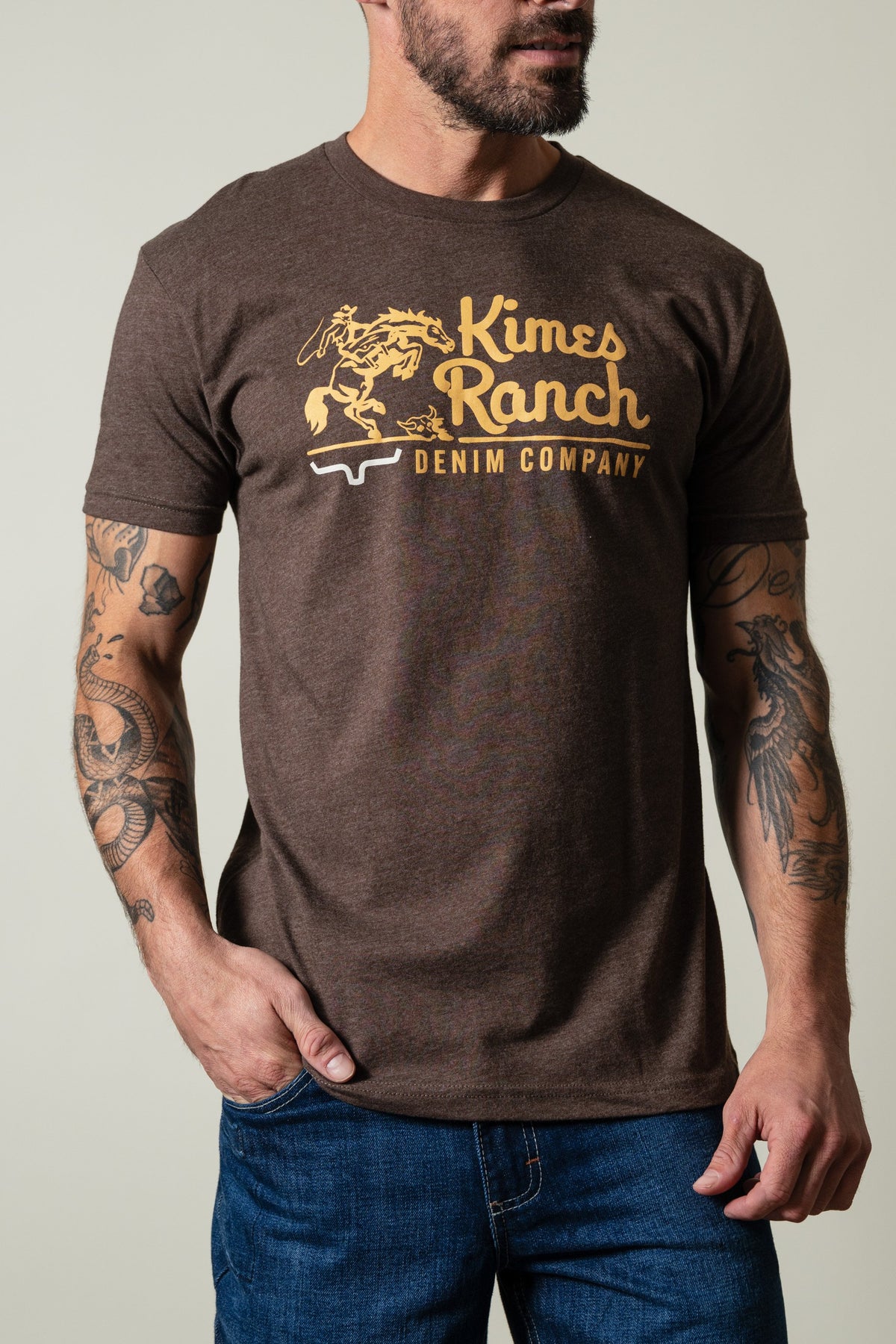 Kimes Ranch Davona Dale Espresso short sleeve shirt with graphic of cowboy on bucking horse and "Kimes Ranch DENIM COMPANY"; #color_espresso