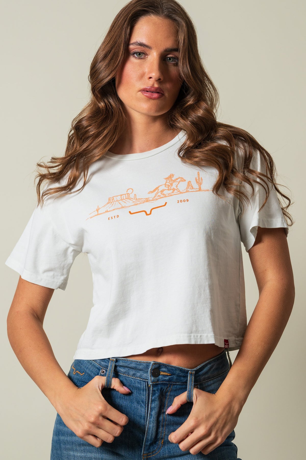 Kimes Ranch Go West Natural shirt with orange graphic of a rider and landscape reading ESTD 2009; #color_natural