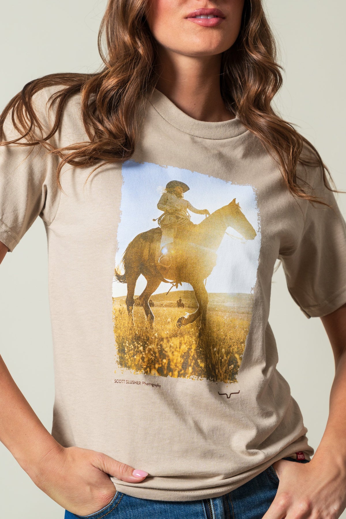 Kimes Ranch SS Riding Sunshine t-shirt in Sand with a graphic of a rider on a horse and SCOTT SLUSHER Photography text; #color_sand